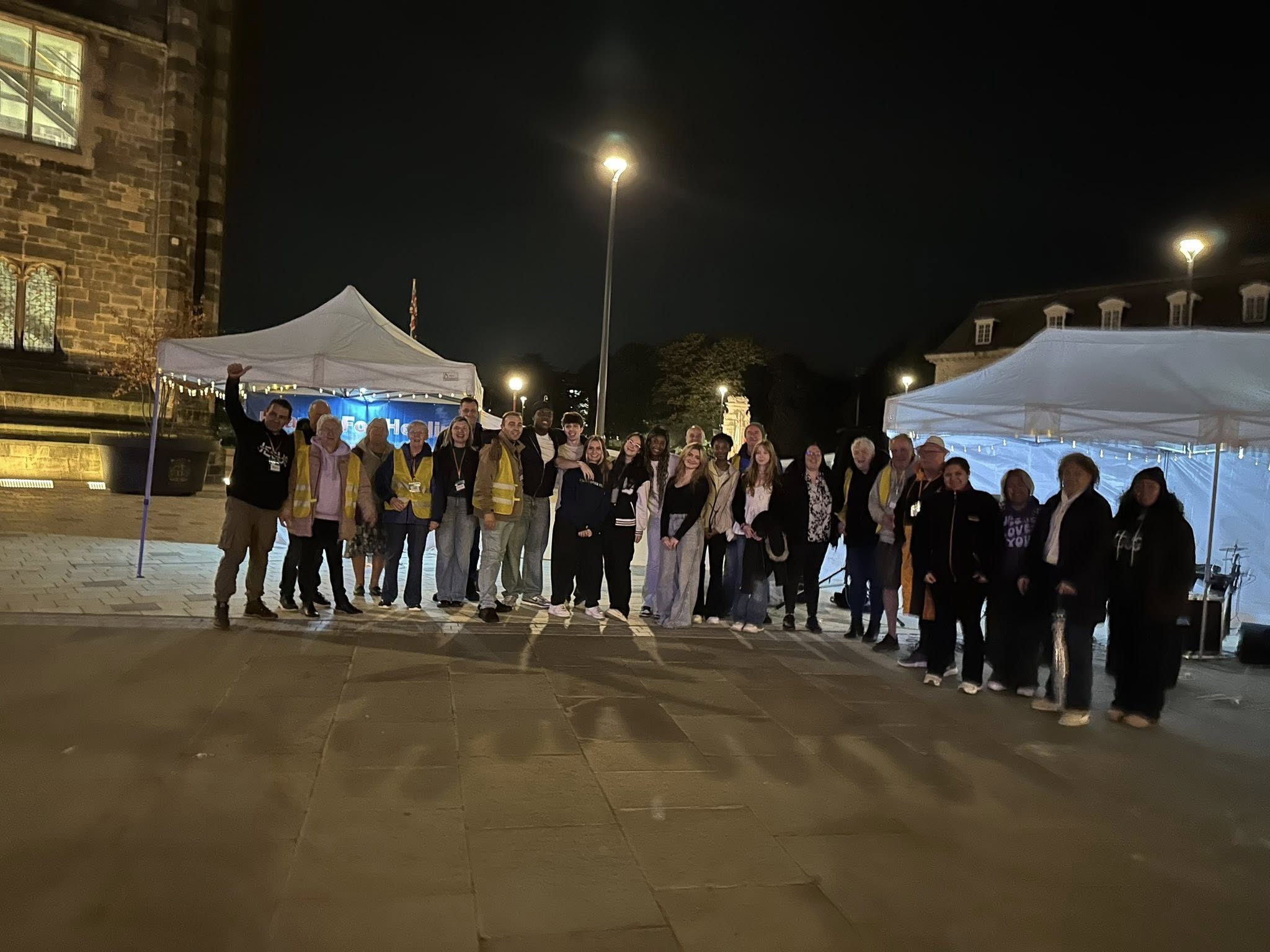 A group of volunteers stand near a gazebo in Rochdale at night